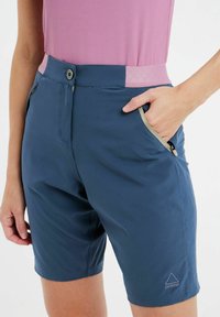 Námořnické modré šortky s kontrastním růžovým pasem, obsahující kapsu na zip a trojúhelníkové logo v dolním rohu. Lehce prodyšný materiál.