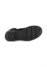 Zwarte schoenzool van gestructureerd rubber, met een profielpatroon voor grip en een subtiele logo. De vorm is rond en iets verhoogd bij de hak.