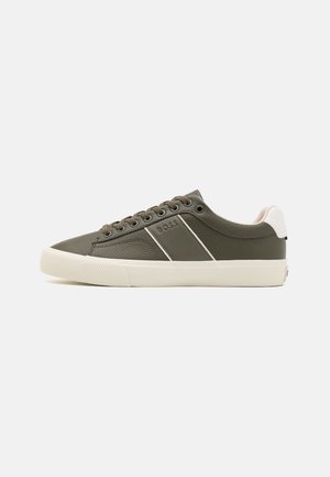 Low-top olijfgroene sneaker met witte zool, veters en hakaccent, met "BOSS" branding op het zijpaneel.