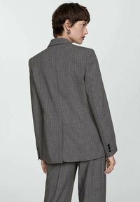 Gray pinstriped blazer with a tailored fit, single vent at the back, lapel collar, and black button accents on the cuffs.