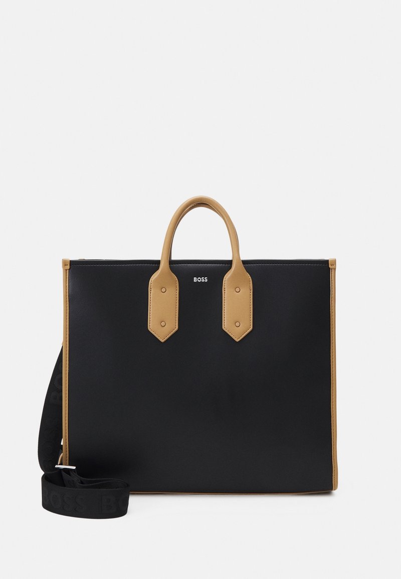 Sac cabas rectangulaire noir avec poignées et finitions couleur camel, petit logo « BOSS » sur le devant, et une bandoulière noire détachable avec marquage embossé.