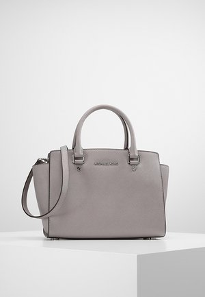 Borsa a mano grigia in pelle Michael Kors con doppi manici e tracolla staccabile, poggiata su un piedistallo bianco contro uno sfondo semplice.