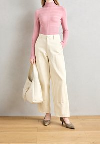 Fitted pink ribbed turtleneck, wide cream trousers, pointed brown heels, and a cream shoulder bag. Smooth textures and simple design.