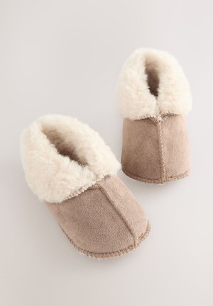 Coppia di pantofole in suede beige con spessa fodera in pile color crema, viste dall'alto su uno sfondo chiaro.