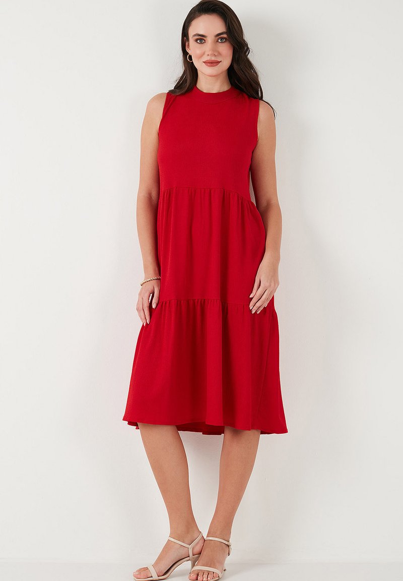 Red sleeveless midi dress with a fitted bodice, tiered skirt design, and soft fabric. Features a round neckline and a flowing silhouette.