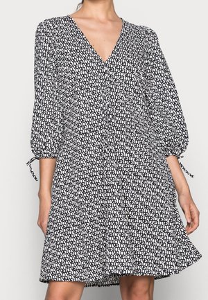 Robe à motif noir et blanc avec un décolleté en V, des manches bouffantes et des accents à cordon aux poignets. Silhouette évasée, tissu léger.