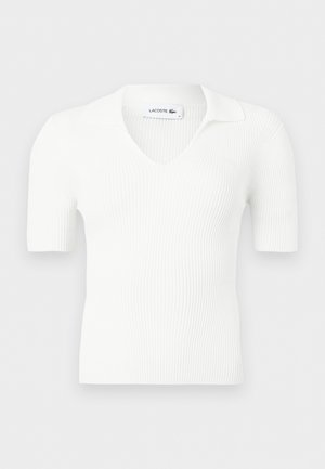 Bijeli džemper s rebrastim uzorkom, kratkih rukava, s V-izrezom i ovratnikom, s natpisom Lacoste unutar vrata.