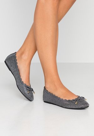 Ballerines grises scintillantes avec des bords en dentelle, détail de nœud au niveau des orteils et semelle plate. La tige est en matériau texturé et brillant.