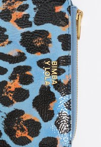 Textūruotas mėlynas maišelis su juodu ir oranžiniu leopardiniu raštu. Aukso "Bimba Y Lola" logotipas ir aukso užtrauktuko akcentas.