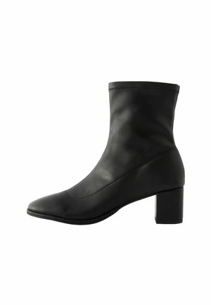 Stivale nero alla caviglia in pelle liscia con punta appuntita, tacco medio a blocco e cuciture subtle lungo il bordo superiore.