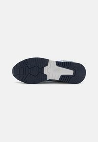 Sola de sapatilha de corrida azul com borracha preta texturizada para aderência, uma entressola branca, e o logótipo da ASICS em letras brancas em relevo.