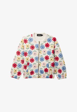 Veste blanche matelassée avec fermeture éclair à l'avant, présentant un motif floral multicolore avec des fleurs rouges, bleues, jaunes et roses, accompagnées de feuilles vertes.