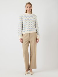 Pull créme avec des motifs en vagues bleues et beiges, associé à un pantalon large beige clair. Stylé avec des escarpins beiges pointus.