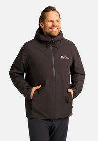 Veste imperméable noire avec capuche, fermeture éclair avant et poches latérales. Comprend des cordons ajustables et un logo sur la poitrine gauche.