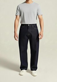 Ciemnoniebieskie dżinsy z widocznym przeszyciem, zestawione z szarym t-shirtem z krótkim rękawem i białymi trampkami. Prosty krój, minimalna ilość detali.