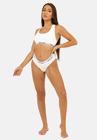 Reggiseno sportivo bianco e culotte a vita alta coordinate, con un elastico nero con il logo "Sixth June". Tessuto liscio con una vestibilità aderente.