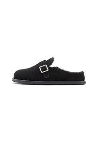 Svart mocka slip-on tofflor med ett spänne, foder av shearling och gummisula; rund tå och utan baksida.