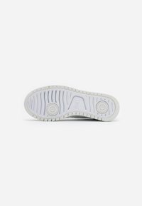 White sneaker sole featuring a textured rubber surface with a circular design element and defined tread pattern for grip.