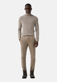 Beżowy sweter z wysokim kołnierzem, beżowe spodnie sztruksowe i czarne靴 z wiązaniem. Slim fit, miękka tekstura, minimalistyczny design i subtelne szwy.