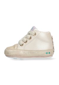 Zapatilla de cuero crema con acentos dorados, puntera redonda, tres ojales para los cordones y una suela suave. Presenta un dorso texturizado y puntos en color teal en el costado.