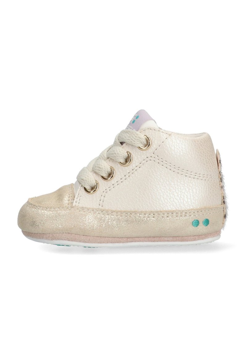 Zapatilla de cuero crema con acentos dorados, puntera redonda, tres ojales para los cordones y una suela suave. Presenta un dorso texturizado y puntos en color teal en el costado.