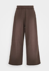 Braune weite Sweatpants mit elastischem Bund, glatter Textur und seitlichen Taschen. Einfaches Design ohne zusätzliche Akzente.