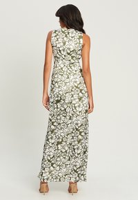 Maxi dress featuring a floral pattern in white on an olive green background. Short sleeves and a fitted design with a flowy, full length.