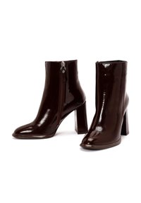 Bottes de cheville bordeaux brillantes avec un bout pointu et un large talon bloc. Dotées d'une fermeture éclair latérale avec des accents rouges pour un enfilage facile.