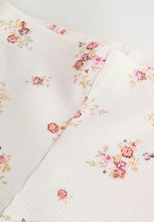 Tissu à motifs floraux avec une texture côtelée dans des tons de rose doux, présentant de petites roses et des accents verts tout au long.