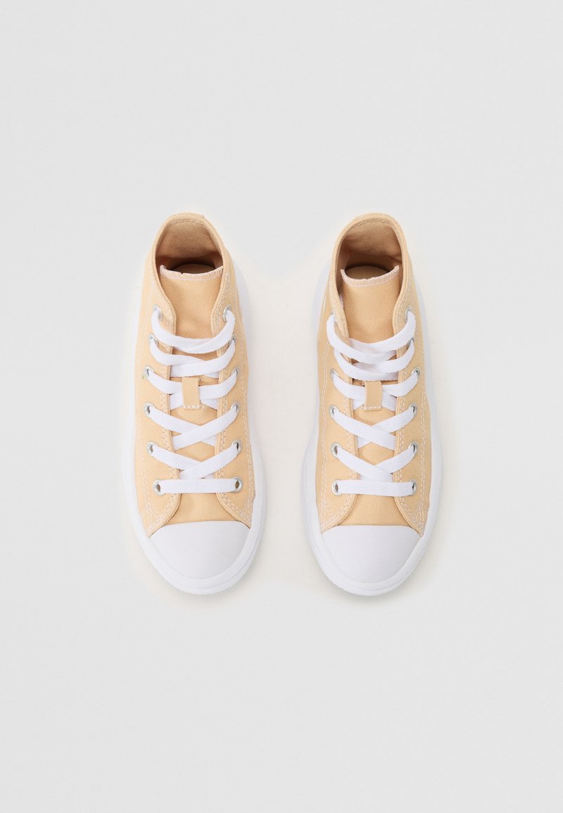Zapatillas de lona beige con punta y suela de goma blanca, que presentan cordones y ojales blancos. Textura suave, diseño bajo.