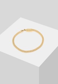Gold chain bracelet with interlocking links, featuring a small rectangular tag engraved with "Kuzoi" and a secure clasp.