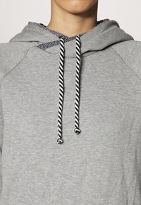 Szary polarowy hoodie z kapturem, z paskami w czarno-białe sznurki oraz miękkim, teksturowanym materiałem.
