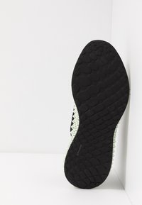 Suela de zapato negra con agarre texturizado y un borde blanco y puntiagudo. El material parece goma con un patrón distintivo de formas ovaladas.