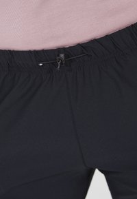 Svarta träningsbyxor har en elastisk midja med dragsko, en slät textur och minimala sömnadsdetaljer.