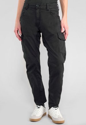 Pantalons cargo noirs en tissu léger, dotés de plusieurs poches latérales et d'un design à jambe fuselée, assortis à des baskets blanches.