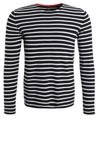 T-shirt à manches longues rayé noir et blanc avec un col rond et un accent rouge au niveau du col, fabriqué en tissu doux.