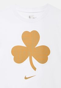 Λευκό T-shirt με μεγάλο χρυσό τριφύλλι με μοτίβο ξύλου και μικρό λογότυπο Nike από κάτω.