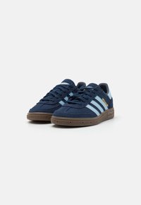 Navy blue suede sneakers with light blue stripes and brown rubber sole. Features lace-up design and padded collar for comfort.