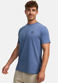Kurzärmliges, Rundhals-T-Shirt aus leichtem blauen Baumwollstoff. Verfügt über ein kleines, dunkelblaues Logo auf der Brust und hat einen entspannten Schnitt.