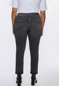 Black denim jeans with a fitted waist, rolled cuffs, and two back pockets. The fabric has a smooth texture with slight distressing on one pocket.
