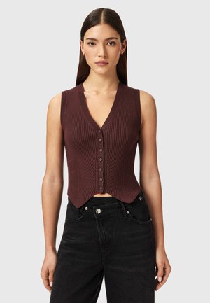 Geribd, diep V-hals, mouwloos topje in donkerbruin met knopen aan de voorkant. Het heeft een cropped zoom en een gestructureerde afwerking. Gecombineerd met zwarte high-waisted jeans.