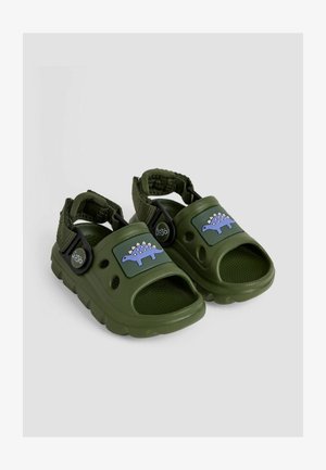 Zelene plastične sandale s grafikom dinosaura, podesivim trakama, otvorenim prstima i reljefnom unutrašnjošću za bolji zahvat. Čvrsta konstrukcija.