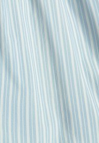 Tissu bleu clair avec de fines rayures blanches verticales, présentant une texture lisse qui crée des plis doux et de subtiles réflexions de lumière.