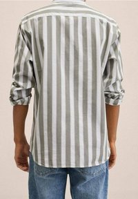Camicia a righe realizzata in tessuto leggero, caratterizzata da strisce verticali alternate di grigio chiaro e bianco, maniche arrotolate e colletto standard.