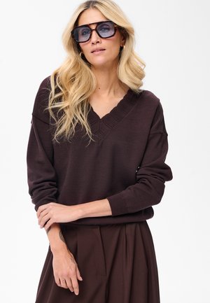 Brauner gestrickter Pullover mit V-Ausschnitt und strukturiertem Kragen, kombiniert mit hoch taillierten braunen Hosen. Verfügt über lange Ärmel und eine lockere Passform.