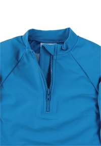 Blue zip-up top made of polyester. Features a high collar, a short zipper, and smooth texture. Sleeves are designed with raglan seams.