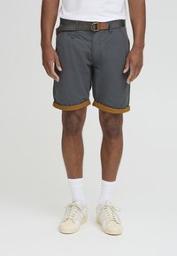Gray shorts with brown rolled cuffs, featuring a front pocket and a belt with a round metal buckle. Worn with white socks and white sneakers.