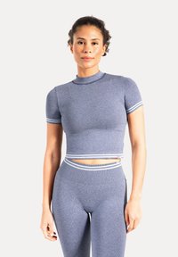 Kortærmet, tætsiddende cropped top i tekstureret blåt stof med hvide striber på ærmerne og bundkanten; kombineret med højttaljede leggings.