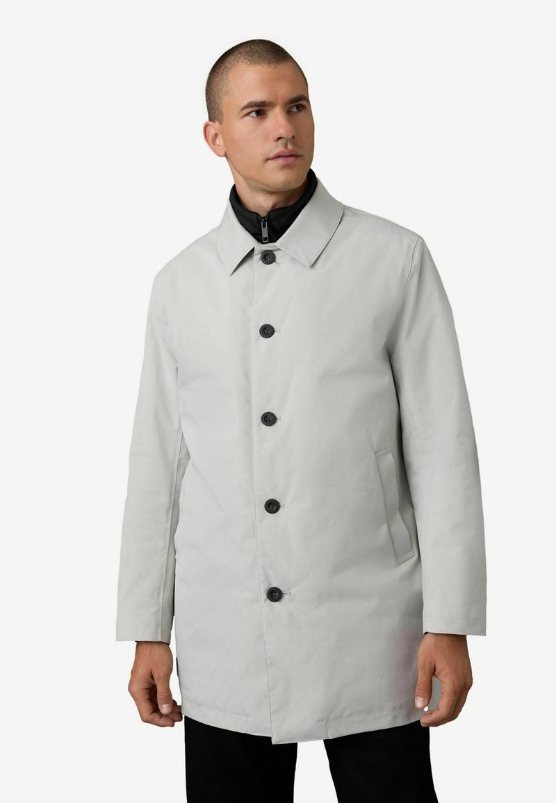 Hellgrauer Trenchcoat mit klassischem Kragen, fünf schwarzen Knöpfen, Seitentaschen und einer glatten Textur. Schwarze Innenauskleidung ist am Kragen sichtbar.