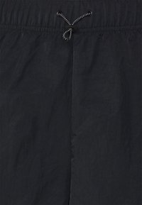 Svarta shorts med dragsko i en mjuk, texturerad tyg. Har en samlad midja och en kontrasterande dragsko för justerbarhet.